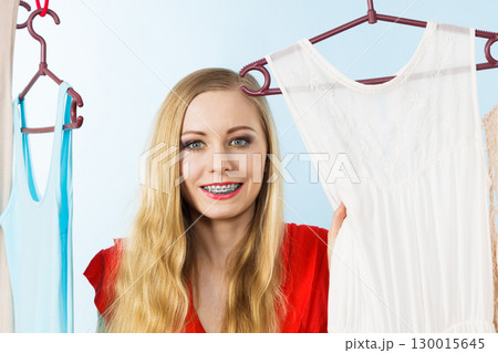 Woman in shop or wardrobe picking dress 130015645