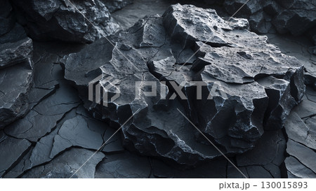Dark rock formation showing cracks and texture in a desolate landscape 130015893