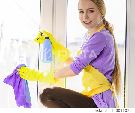 Girl cleaning window at home 130016076