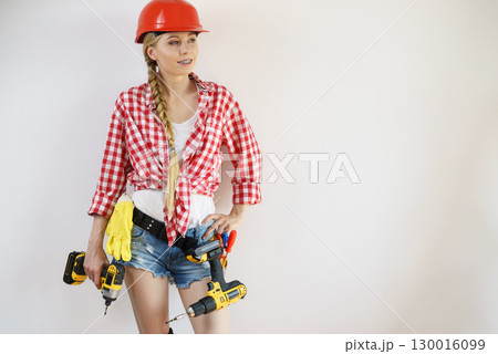 Woman wearing helmet using drill 130016099