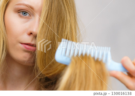 Blonde girl combing her long messy hair 130016138