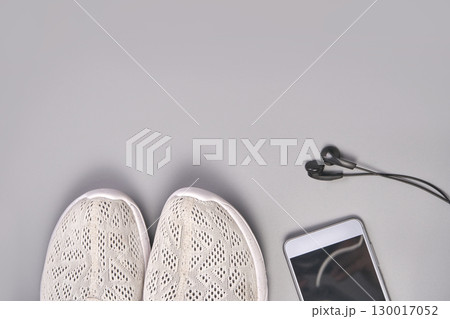 White sneakers with smartphone and earbuds on gray surface 130017052