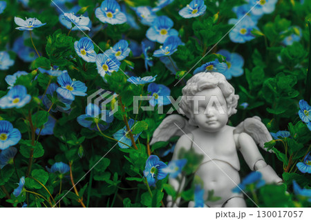 Cupid figurine in Veronica Georgia blue flowers, soft focus 130017057