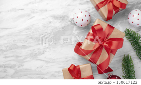 Gift box with red bow, christmas present with ball and leaves decor on marble table background, top view 130017122
