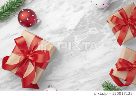 Christmas present, gift box with red bow with ball and leaves decor on marble table background, top view 130017123