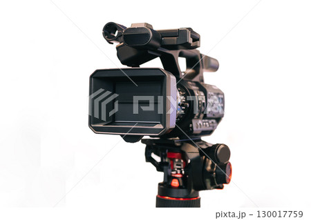 Professional digital video camera with accessories, mounted on a tripod. The camera is equipped with a lens and an external battery. Video camera on a white background, isolated. Video shooting. 130017759