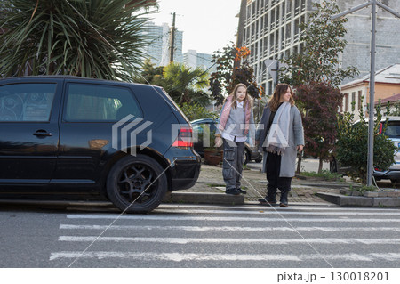Happy woman and young child girl standing on crosswalk Happy woman and young child girl standing on crosswalk 130018201