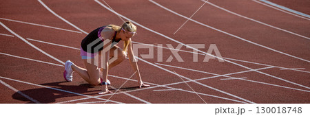 Female sprinter prepares to race on a track with intense focus and determination. Banner 130018748