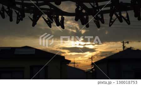 ベランダから眺める夕焼け空。洗濯バサミにピント。 130018753