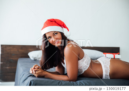 Woman in lingerie with gift in bedroom on bed for new year 130019177