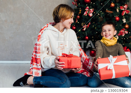 Mom and son decorating Christmas tree with gifts and toys Mom and son decorating Christmas tree with gifts and toys 130019304