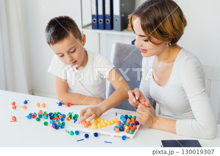 teacher engaged with boy educational games on the table 130019307