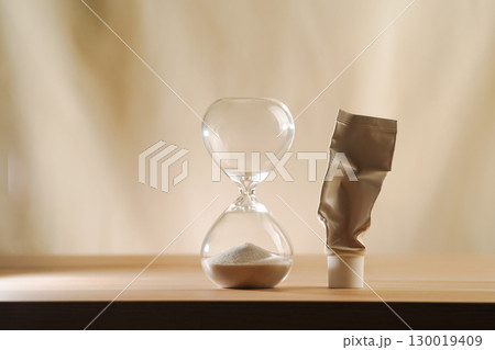 Hourglass with no time left and empty cream tube. Minimalist beige skincare aging concept 130019409