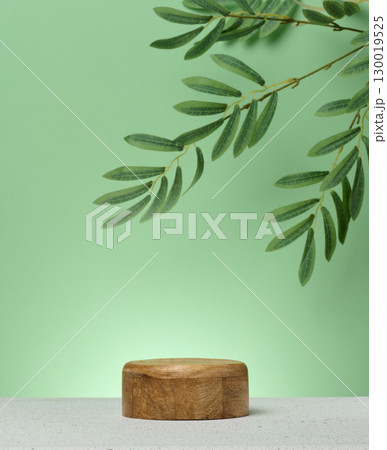 Wooden cylindrical podium or display stand sits on green background. Wooden cylindrical podium or display stand sits on green background. 130019525