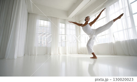 Graceful Ballet Dancer Practicing Balance in Bright Studio Space Graceful Ballet Dancer Practicing Balance in Bright Studio Space 130020023