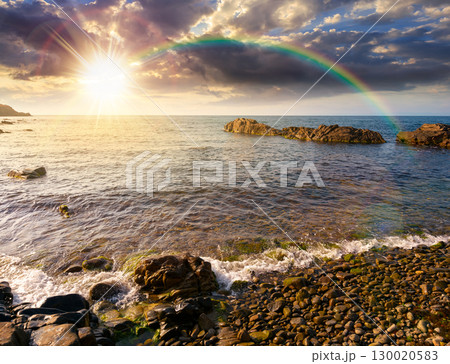 pebble coast at sunset under the rainbow. beautiful summer vacation season at the sea in evening light pebble coast at sunset under the rainbow. beautiful summer vacation season at the sea in evening light 130020583