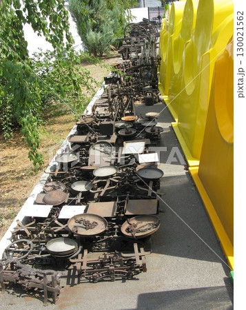 Outdoor Display of Vintage Scale Collection Lined Up Against Yellow Structures 130021562
