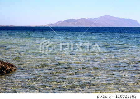 Coastal Scene with a Solitary Rock in Shallow Water and Mountain Backdrop Coastal Scene with a Solitary Rock in Shallow Water and Mountain Backdrop 130021565