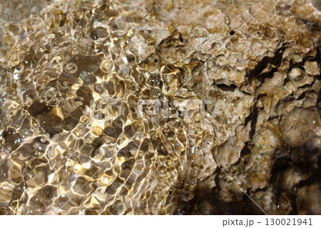 Sunlit Shallow Water Reflecting on a Textured Rocky Surface 130021941