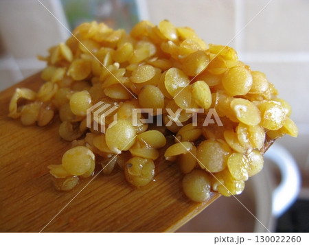 Wooden Spoon Holding Cooked Lentils with a Glossy Texture in a Kitchen Setting Wooden Spoon Holding Cooked Lentils with a Glossy Texture in a Kitchen Setting 130022260