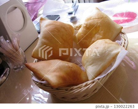 Wicker Basket with Golden Fried Dough Pieces on a Table with Dining Accessories 130022263