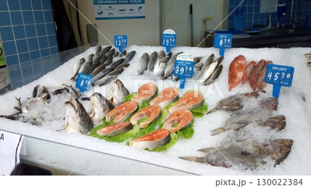 Fresh Salmon Steaks and Whole Fish on Ice at a Market with Blue Tiled Background 130022384
