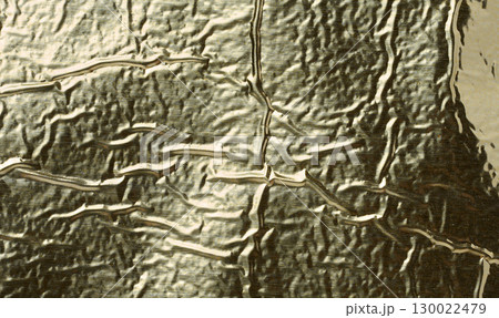 Texture of shiny gold foil with numerous wrinkles and folds. Texture of shiny gold foil with numerous wrinkles and folds. 130022479