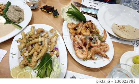 Seafood Feast on a Table with Grilled Shrimp, Fried Squid, and Fresh Veggies Seafood Feast on a Table with Grilled Shrimp, Fried Squid, and Fresh Veggies 130022798