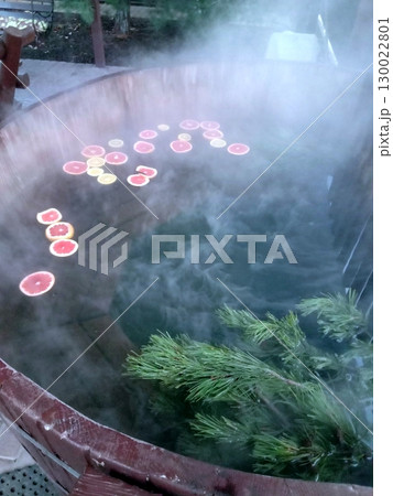 Steamy Hot Tub with Floating Citrus Slices and Pine Branches in a Relaxing Setting Steamy Hot Tub with Floating Citrus Slices and Pine Branches in a Relaxing Setting 130022801