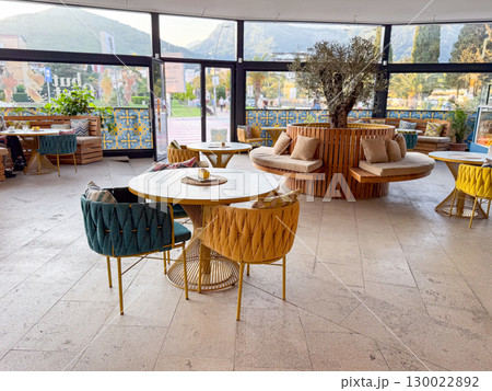 Modern cafe interior with stylish furniture and tree decor. Space reflects leisure, hospitality and urban lifestyle. Modern cafe interior with stylish furniture and tree decor. Space reflects leisure, hospitality and urban lifestyle. 130022892