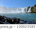 View of a beautiful waterfall from a rocky shore 130023585