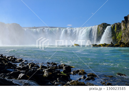 View of a beautiful waterfall from a rocky shore 130023585