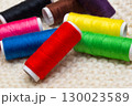 A set of colored threads for sewing on spools. A stack of multi-colored spools of thread 130023589