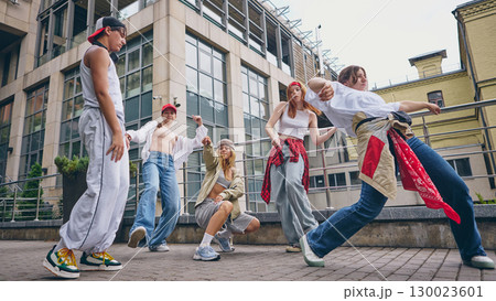 Street dance crew performing expressive moves with style and confidence outdoors 130023601