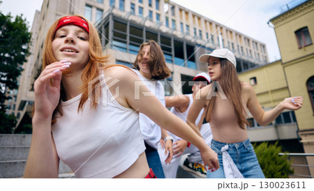 Redhead female street dancer smiling in front of group during performance 130023611