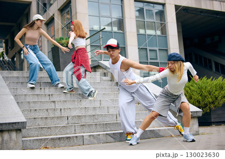 Street dance group performing energetic moves on city stairs with focus and passion 130023630