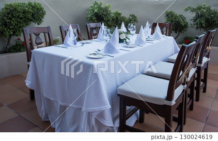 Festively laid table with white tablecloths glasses and plates Festively laid table with white tablecloths glasses and plates 130024619