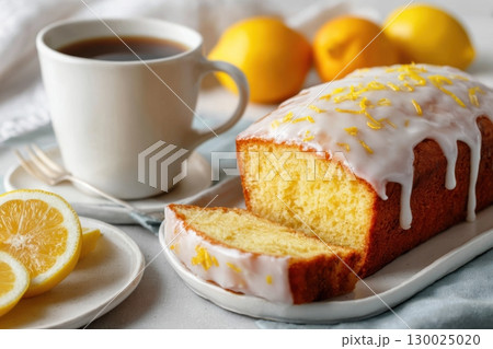 Homemade lemon drizzle cake with icing. Classic lemon pound cake with citrus glaze and zest. Whole loaf, side view, close up. Fresh homemade baked dessert with lemon slices. Blurred tea set background Homemade lemon drizzle cake with icing. Classic lemon pound cake with citrus glaze and zest. Whole loaf, side view, close up. Fresh homemade baked dessert with lemon slices. Blurred tea set background 130025020