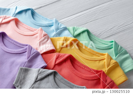 Baby onesie set. White wooden background. Fashion newborn clothes. Top view. Kids soft clothing. Infant trendy cotton bodysuit. Pastel color. Gender neutral. Variety stylish child wear sale. Kid dress 130025510