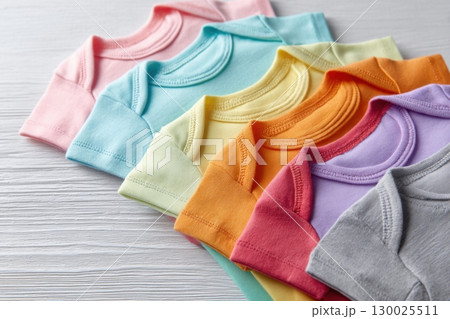 Baby onesie set. White wooden background. Fashion newborn clothes. Top view. Kids soft clothing. Infant trendy cotton bodysuit. Pastel color. Gender neutral. Variety stylish child wear sale. Kid dress 130025511