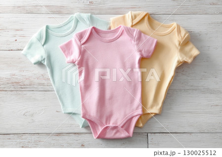 Baby onesie set. White wooden background. Fashion newborn clothes. Top view. Kids soft clothing. Infant trendy cotton bodysuit. Pastel color. Gender neutral. Variety stylish child wear sale. Kid dress 130025512