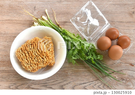 dry instant noodles on bowl with raw egg in plastic packaging and spring onion couple parsley prepare to cooking dry instant noodles on bowl with raw egg in plastic packaging and spring onion couple parsley prepare to cooking 130025910