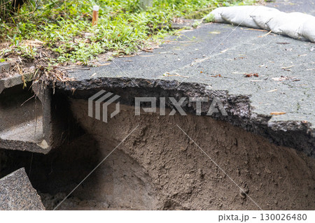 大雨の被害でアスファルトの道路が崩れている 130026480