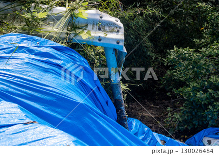 大雨被害で道路が崩れていてブルーシートで養生している現場 130026484
