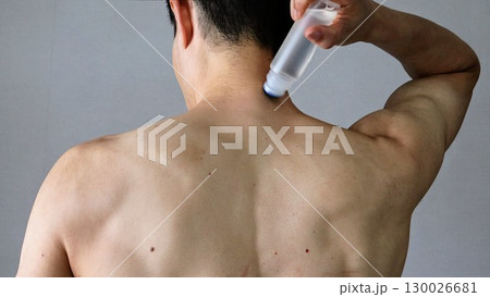 身体に湿布を塗る人物の後ろ姿 130026681