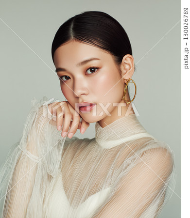 ゴールドイヤリングと透け感トップスが映える日本人女性のポートレート（ファッション 美容 広告） 130026789