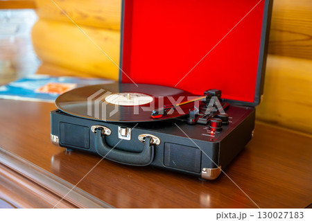 Vintage suitcase-style record player spinning vinyl record. Retro music in motion creating nostalgic atmosphere in home interior Vintage suitcase-style record player spinning vinyl record. Retro music in motion creating nostalgic atmosphere in home interior 130027183