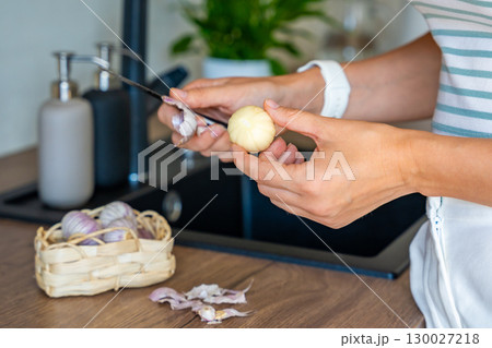 Female hands peeling Chinese single clove garlic on kitchen countertop. Cooking process, natural seasoning, and preparation of fresh ingredient. Female hands peeling Chinese single clove garlic on kitchen countertop. Cooking process, natural seasoning, and preparation of fresh ingredient. 130027218