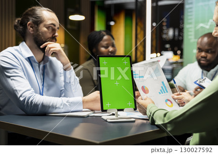 Coworkers hosting business meeting at night with green screen in the strategy room of a multinational firm, reviewing proposals and updates. Making decisions for organization future. 130027592