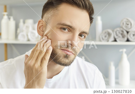 Young man smearing moisturizing cream for skin hydration during skin care routine in morning Young man smearing moisturizing cream for skin hydration during skin care routine in morning 130027810